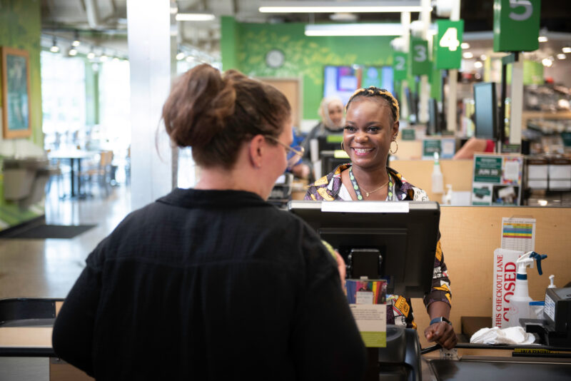 A Seward Co-op staff member helping a customer at the register