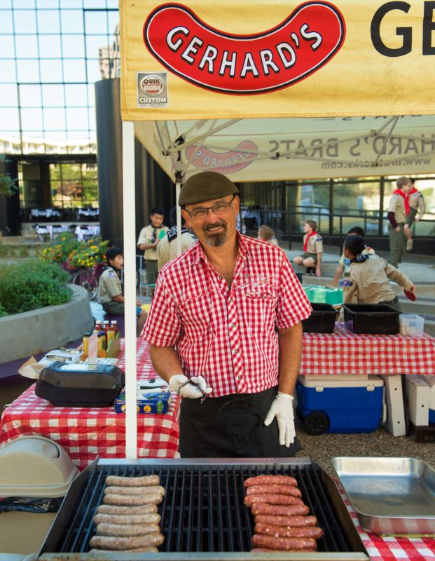 A person cooking brats on a grill