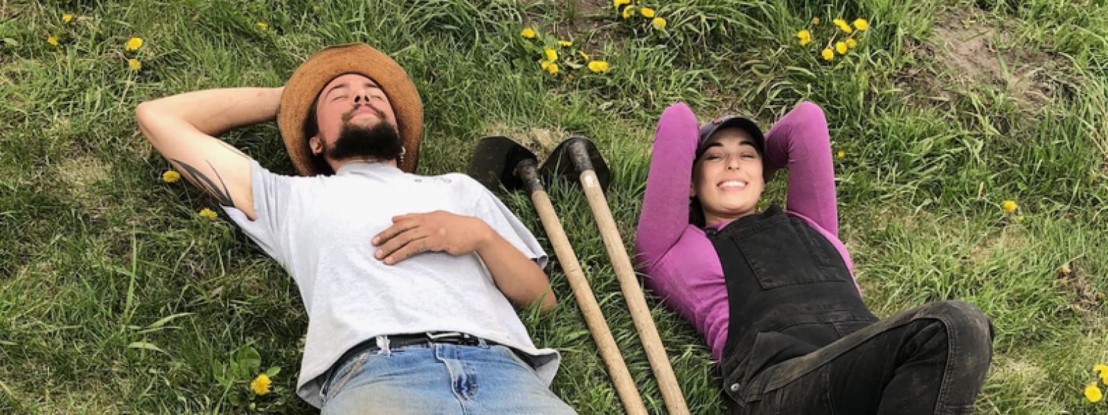 Two people lying on their backs on the ground and smiling