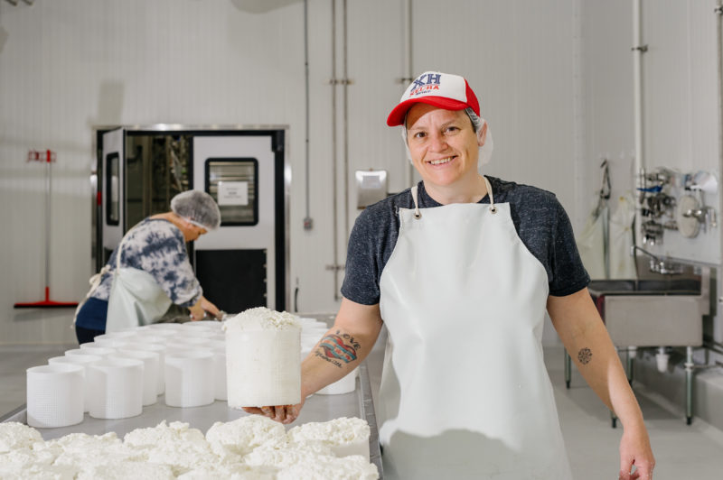 A person smiling next to a table full of white goat cheese