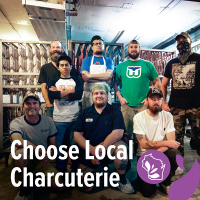 A group of people standing in a room with salami and text overlay that reads "Choose Local Charcuterie"