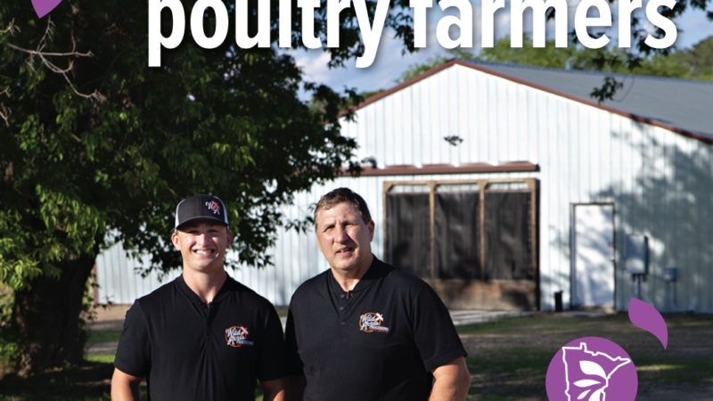 Two poultry farmers stand in front of a white building. Both are wearing black shirts and are smiling. Text overlaid on the photo says "Support local poultry farmers".