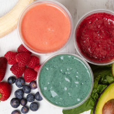 An overhead shot of smoothies and fruit on a white background