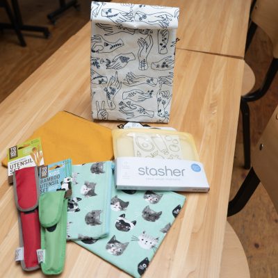 lunch bag, reusable utensils, and washable snack bags on a long wooden table
