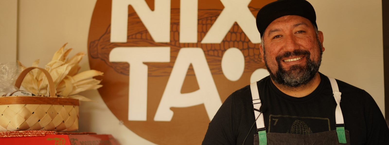 Gustavo in front of Nixta logo, smiling