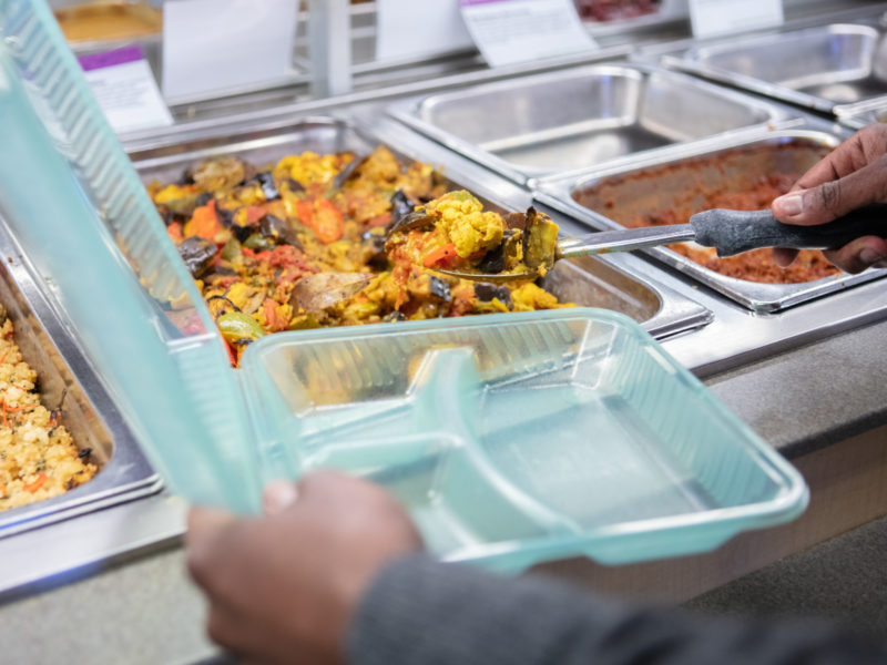 A person getting the Hot Bar in a reusable container