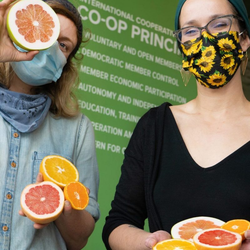 two people wearing masks holding halved citruses