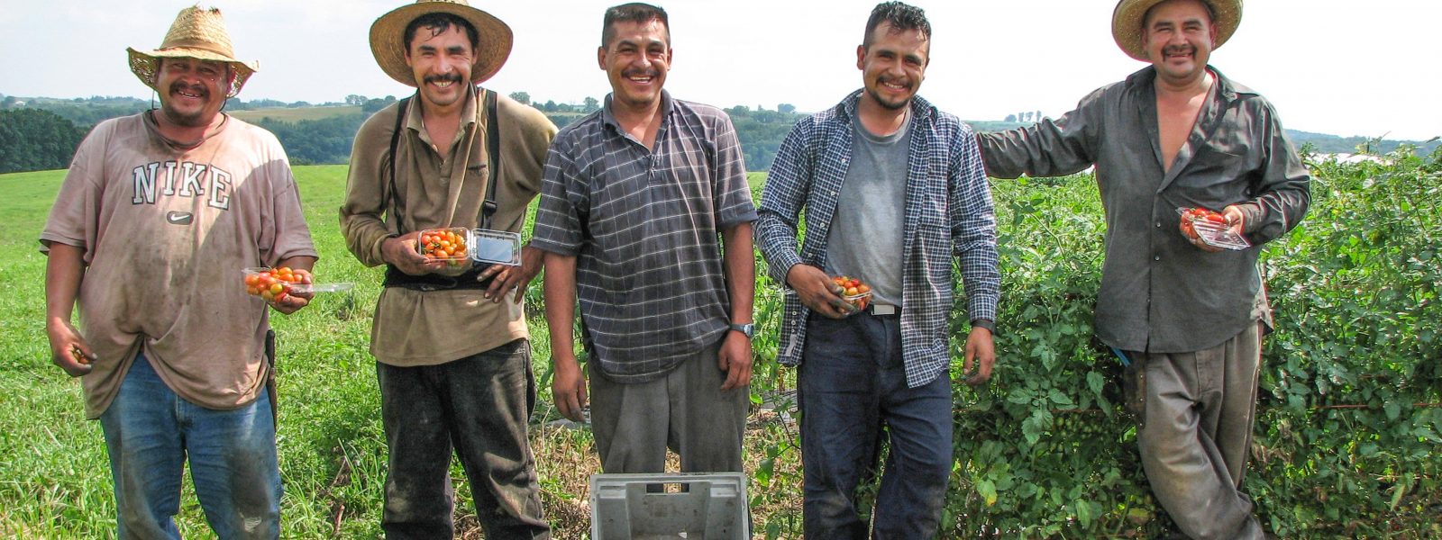A group of farmworkers standing in a field smiling