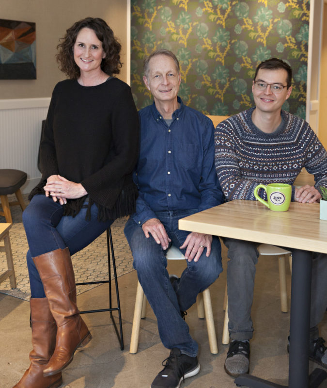 Three people sitting at a table and smiling