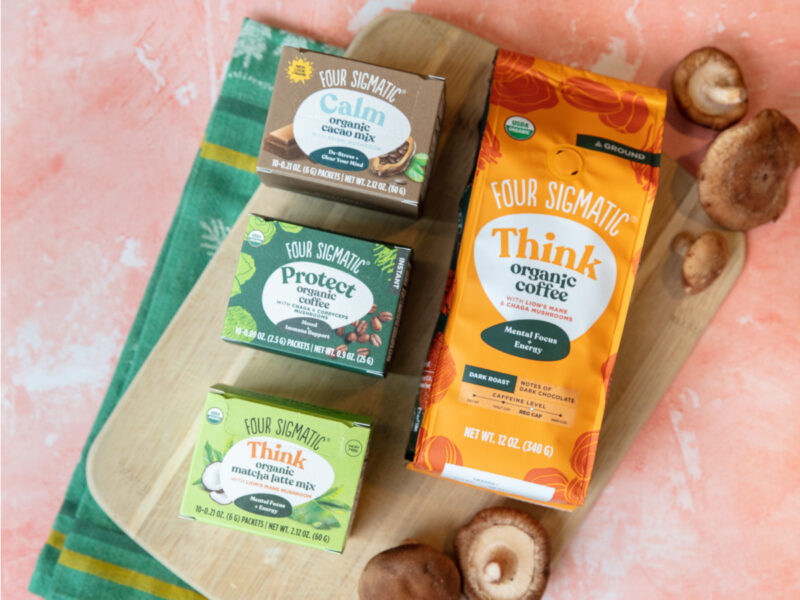 A photo of Four Sigmatic products and mushrooms on a pink background