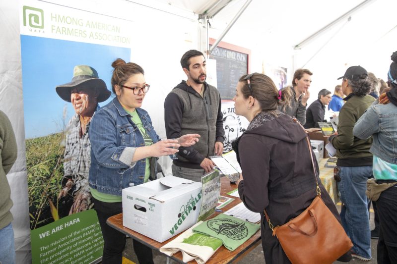 Farmers and CSA Fair visitors talk over a table