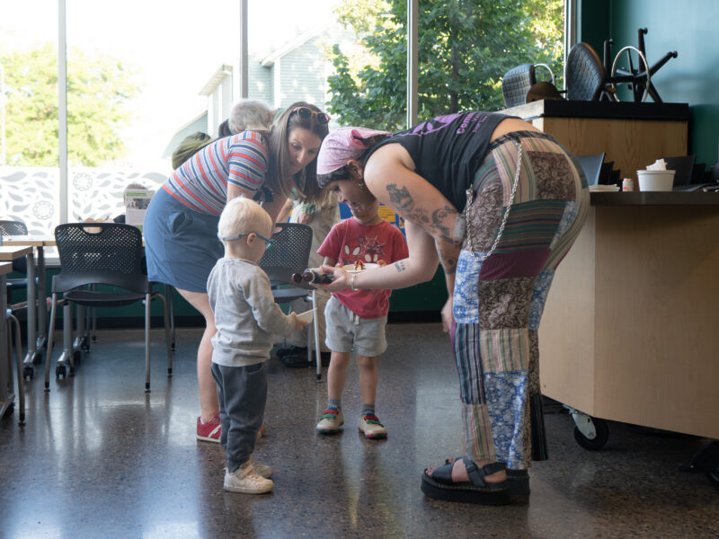 person helping children with ice cream toppings