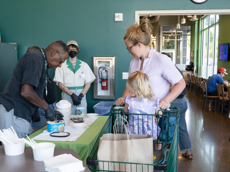 board member talking to shopper and scooping ice cream