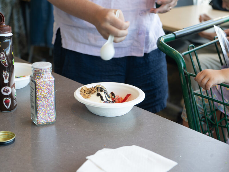 close up of a hand and a bowl of ice cream with toppings on it