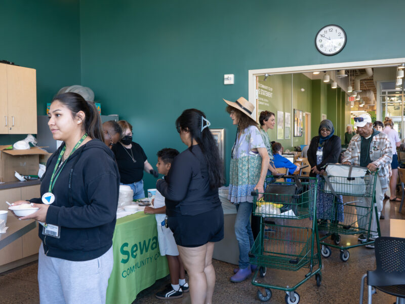 a line of people in the classroom leading into the seating area at Seward Co-op Friendship store