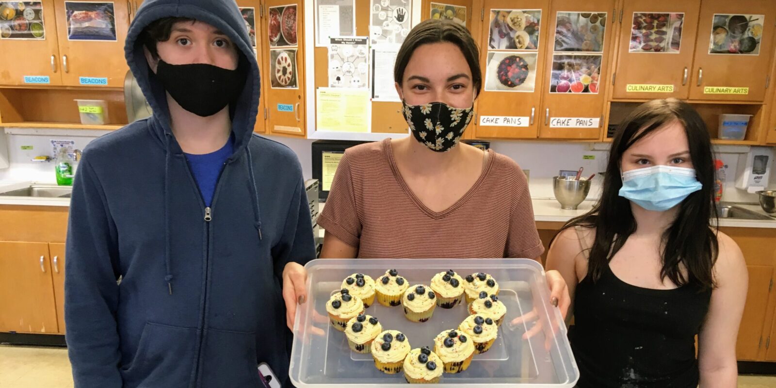 Three teenagers showing off a dish they made in the kitchen