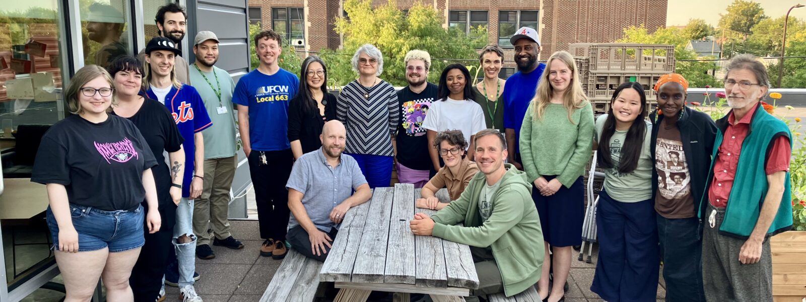 Group of people sitting and standing around a picnic table, members of the Seward Co-op Leadership and UFCW 663 bargaining team