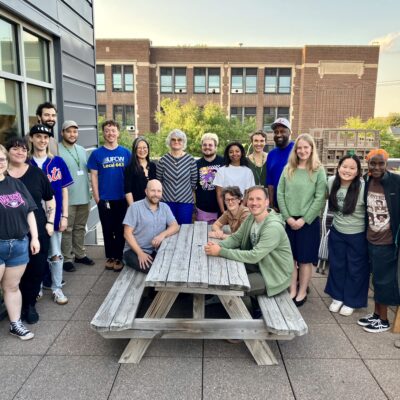 Group of people sitting and standing around a picnic table, members of the Seward Co-op Leadership and UFCW 663 bargaining team