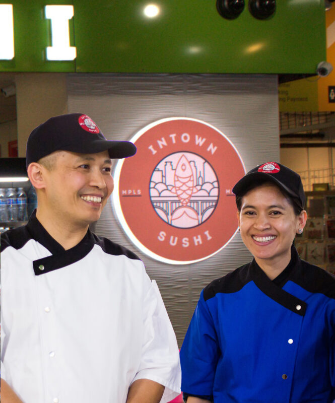 Photo of two people smiling with the Intown Sushi logo in the background