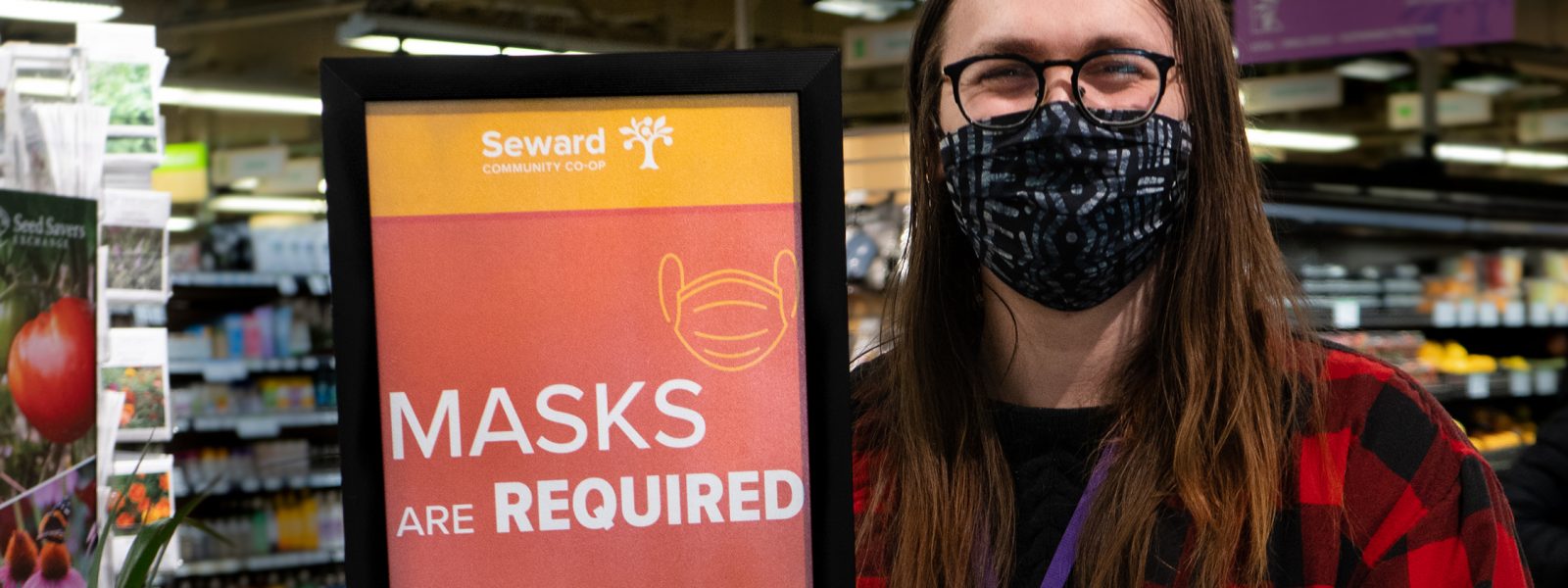 person standing next to a "masks required" sign