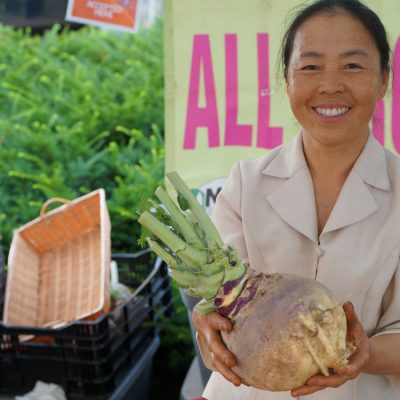 A person holding produce and smiling at the camera