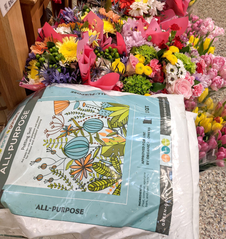 A photo of soil from Mother Earth Gardens next to colorful flowers