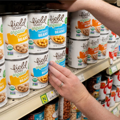 A person arranging cans of food on a shelf