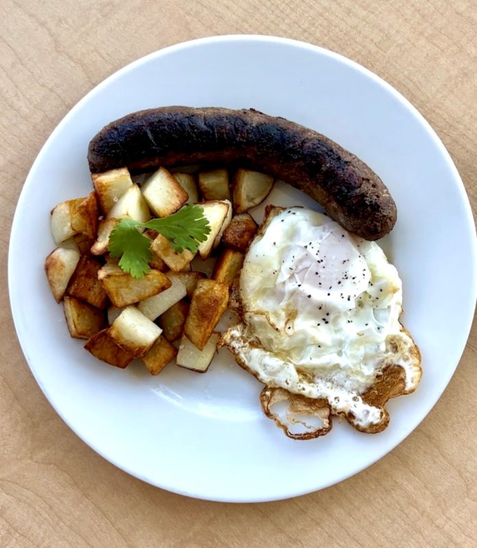 A plate of sausage with an egg and fried potatoes