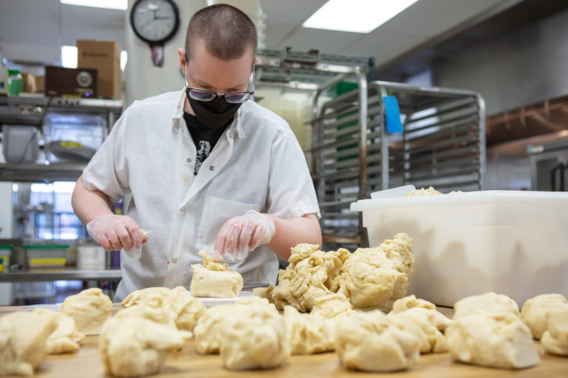 A staff member in the Seward Co-op Bakery weighing dough
