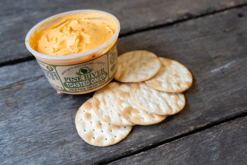 A yellow cheese spread in a tub next to crackers