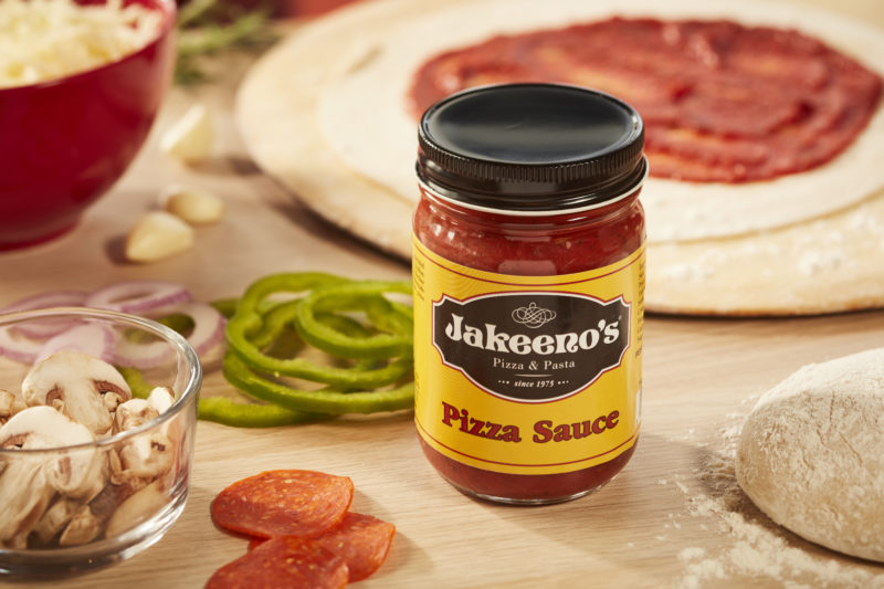 A jar of Jakeeno's pizza sauce next to pizza ingredients