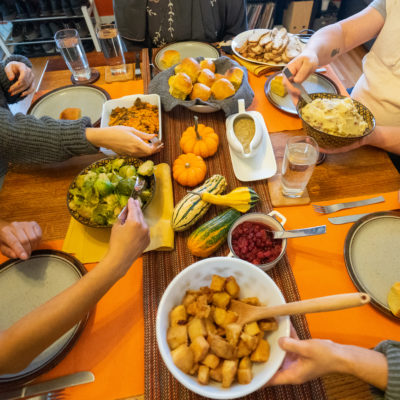 Hands passing harvest dishes around a festive table