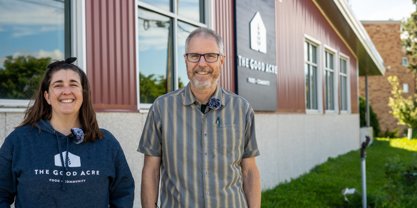 Two people standing next to a red building and smiling