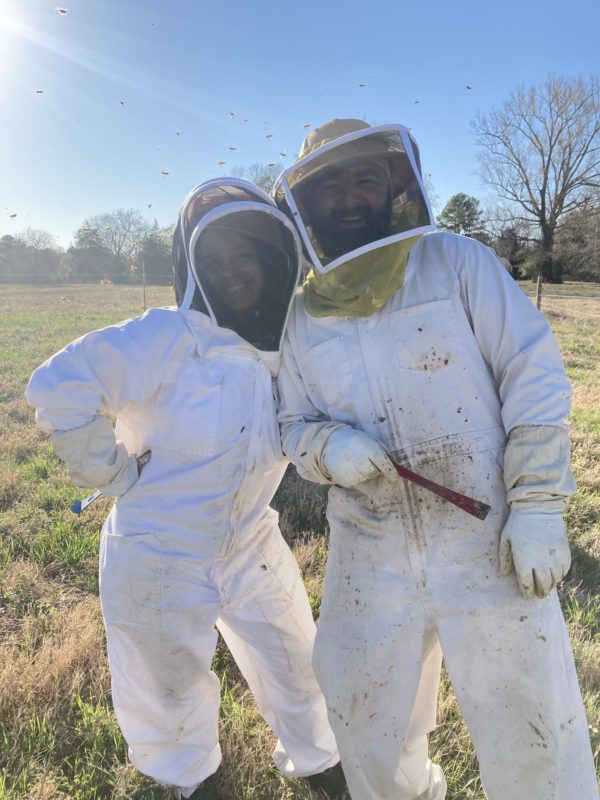 Two people in beekeeping suits posing for a photo
