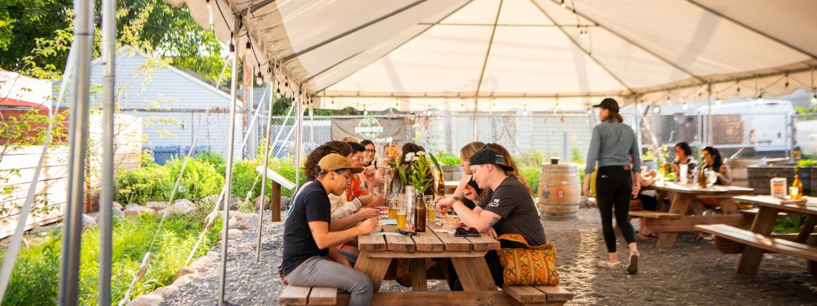 people sitting outdoors under a tent enjoying a meal