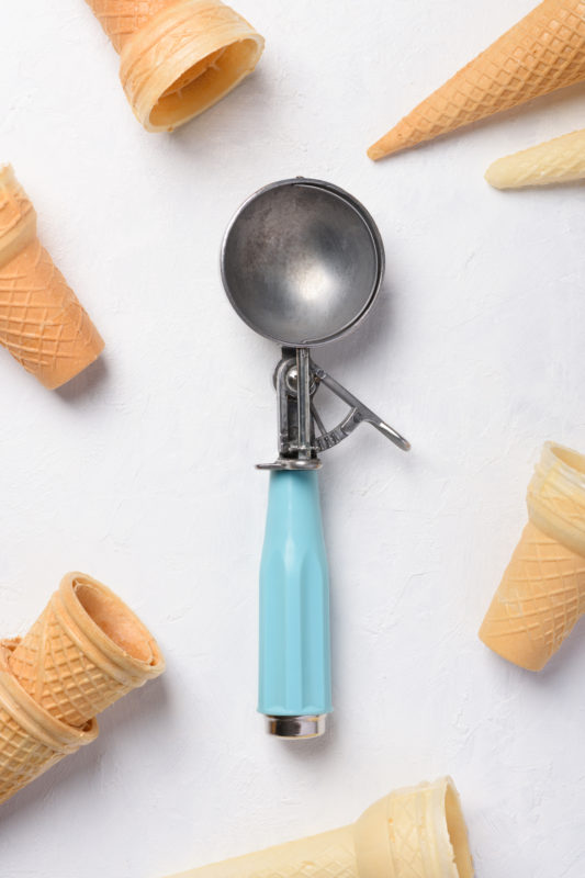 An ice cream scoop surrounded by cones