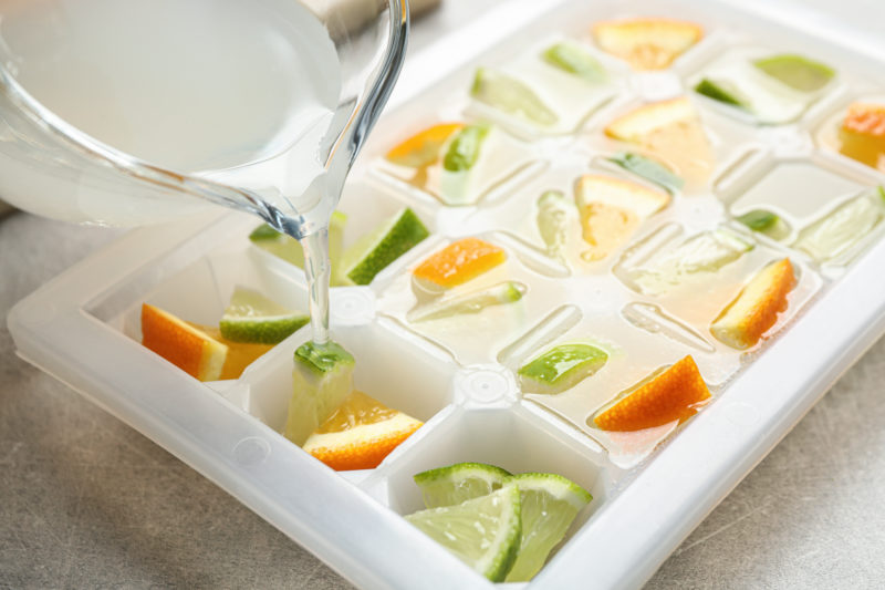 An ice cube tray filled with juice and fruit