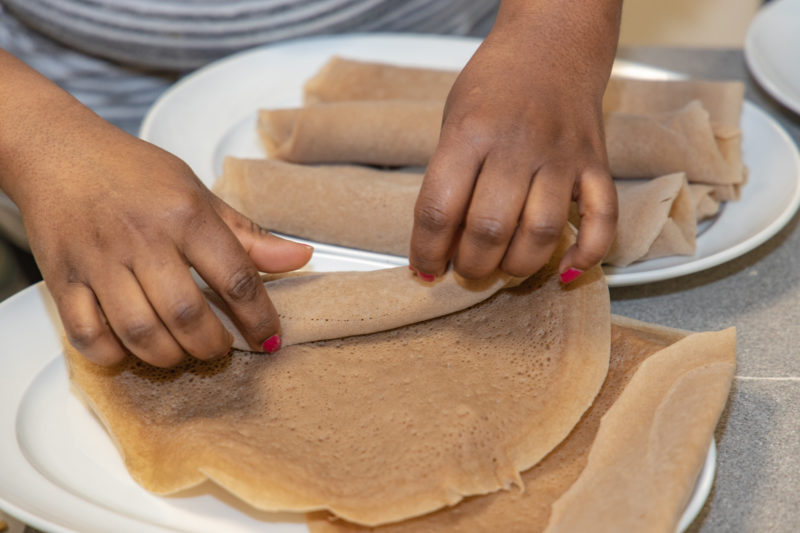 A person rolling pieces of injera