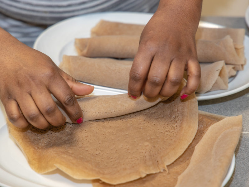A person rolling pieces of injera