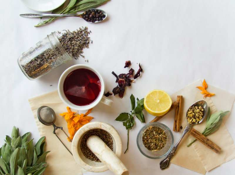 An overhead photo of a cup of tea and various herbs